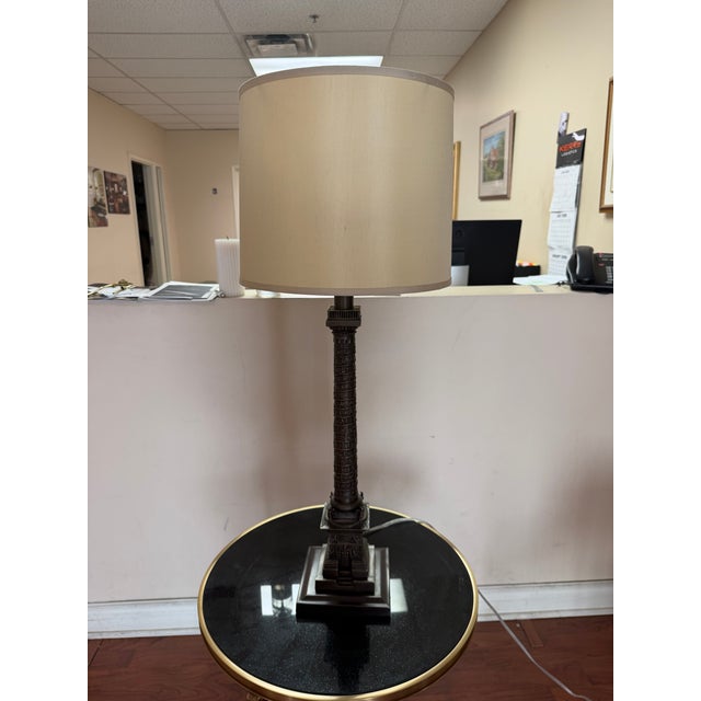 A Haig table lamp featuring a solid brass column inspired by the Vendôme Column in Paris, finished in a bronze patina and...