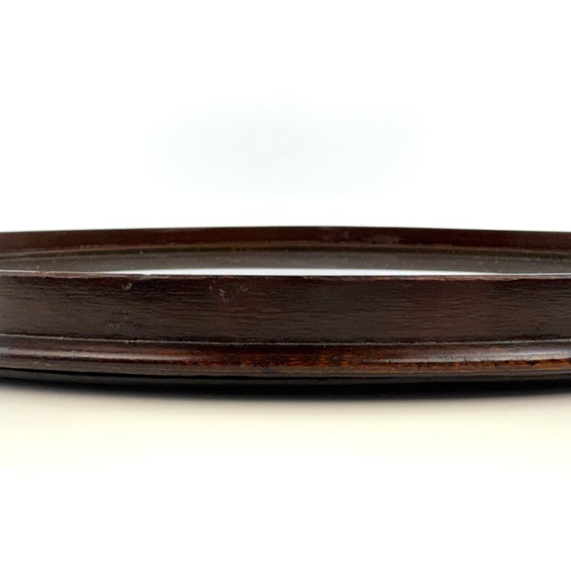 An elegant early 20th-century oval mahogany serving tray featuring finely executed classical inlay and substantial brass...