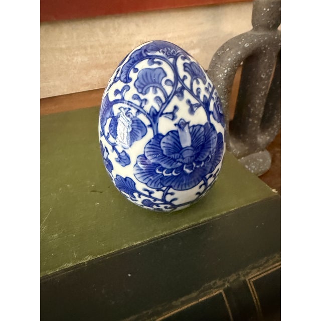 This vintage blue and white chinoiserie porcelain egg features an elegant floral and scrolling vine motif inspired by...