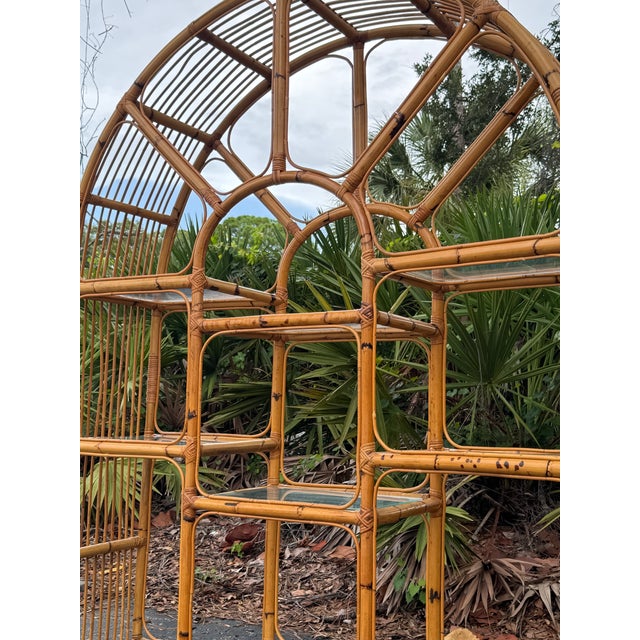 An exceptional vintage 1970s arched bamboo étagère featuring a striking architectural silhouette and original glass...