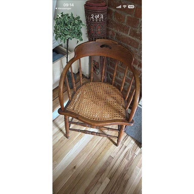 Charming vintage Windsor-style armchair featuring a sculptural curved wood frame, turned spindle details, and a hand-caned...