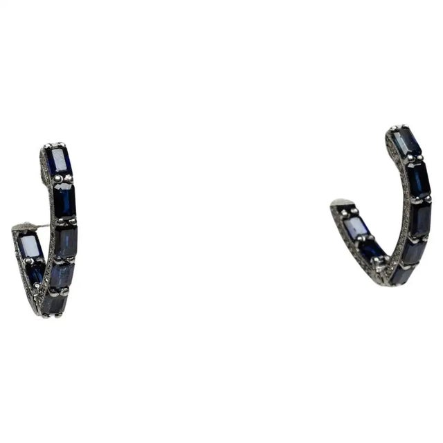A stunning pair of V-shaped blue sapphire hoops. The sapphires are an emerald-cut with an inside-out design so that the...