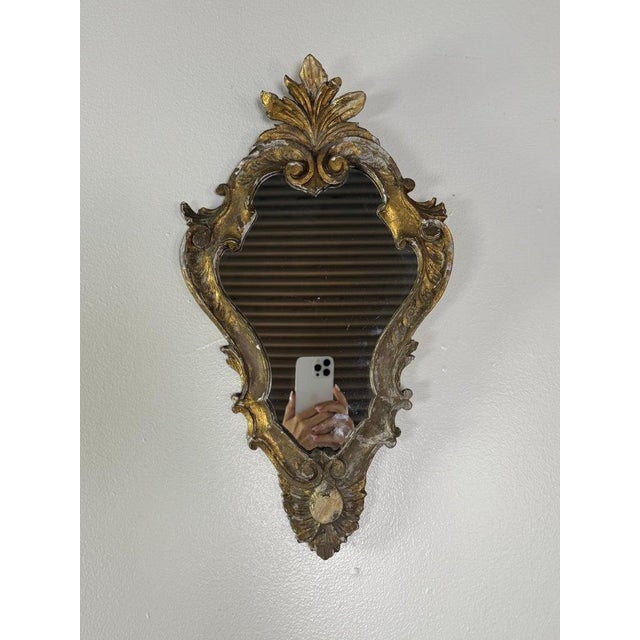 An exquisite Italian Rococo giltwood wall mirror, dating to early 19th century, richly carved with fluid C-scrolls,...