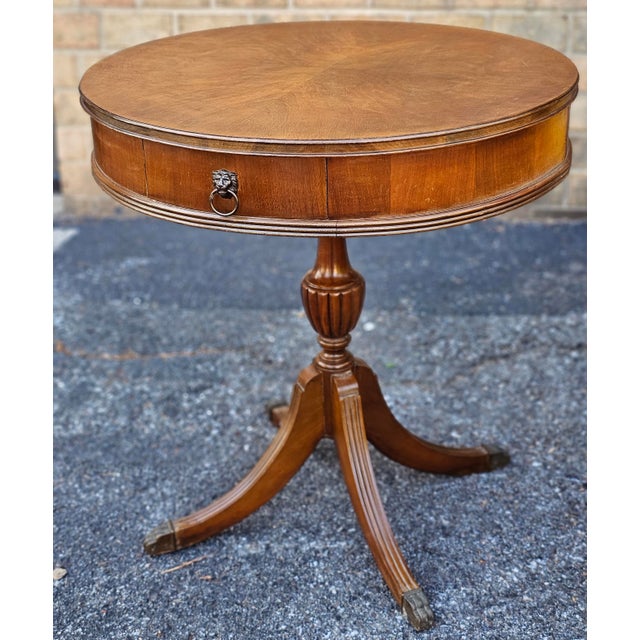 A George III Style Mahogany Two-Drawer Drum Table on quad-leg pedestal terminating with brass cap paw feet. Measures 26"...