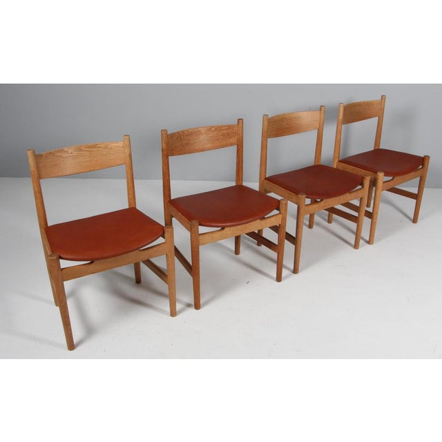 Hans J. Wegner set of four dining chairs in solid soap treated oak, upholstered with tan full grain aniline leather. Model...