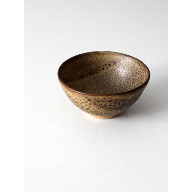 A vintage handmade studio pottery bowl featuring a warm, speckled glaze and a softly rounded form, signed Cohn on the...