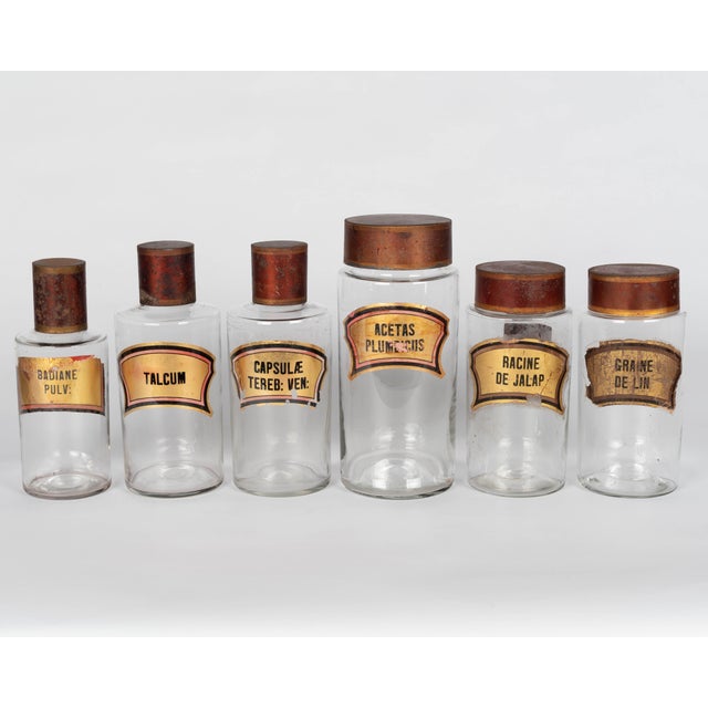 A set of six 19th century French glass apothecary jars or bottles with red painted tin lids. Hand-blown clear glass....