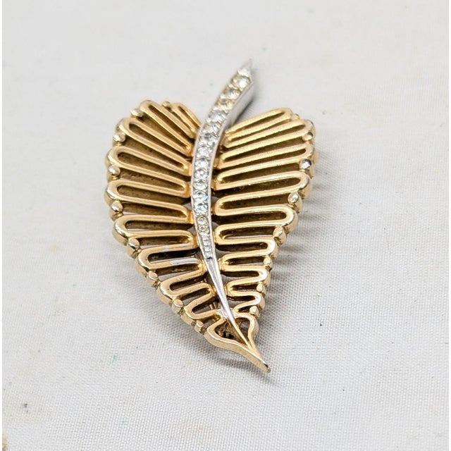 1950s goldtone looped leaf with line of round clear rhinestones down the center brooch with security clasp. Marked...