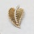 1950s goldtone looped leaf with line of round clear rhinestones down the center brooch with security clasp. Marked...