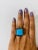 A unique stunner! This ring has a large 9.45 Carat Cushion Cut Turquoise and is surrounded by 22 Pave Set Black Round Cut...