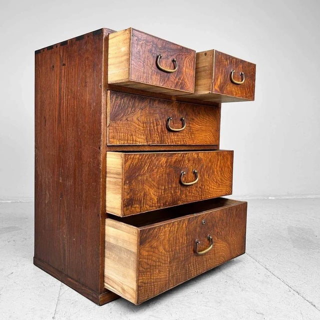 Small Japanese Tansu from the 1920s with five drawers and beautifully grained wood. The drawers feature copper handles. An...