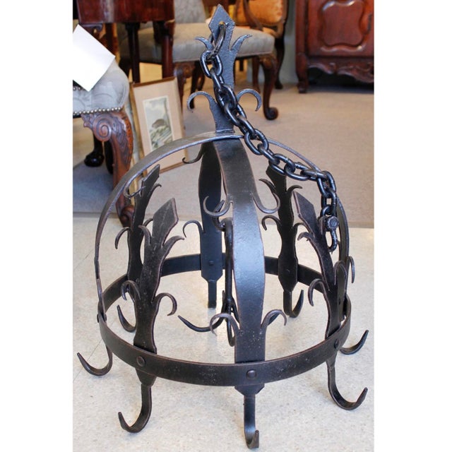 A half dome shaped pot rack, a Continental shape known as a "Dutch crown," featuring fleur-de-lys and scrolling decorative...