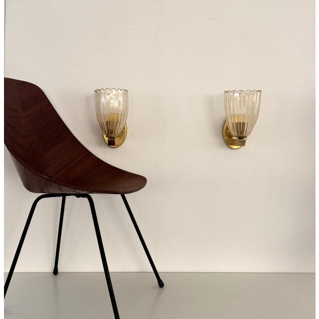 Beautiful set of two brass wall lamps made of strong brass base and light amber colored murano glasses with real golden...