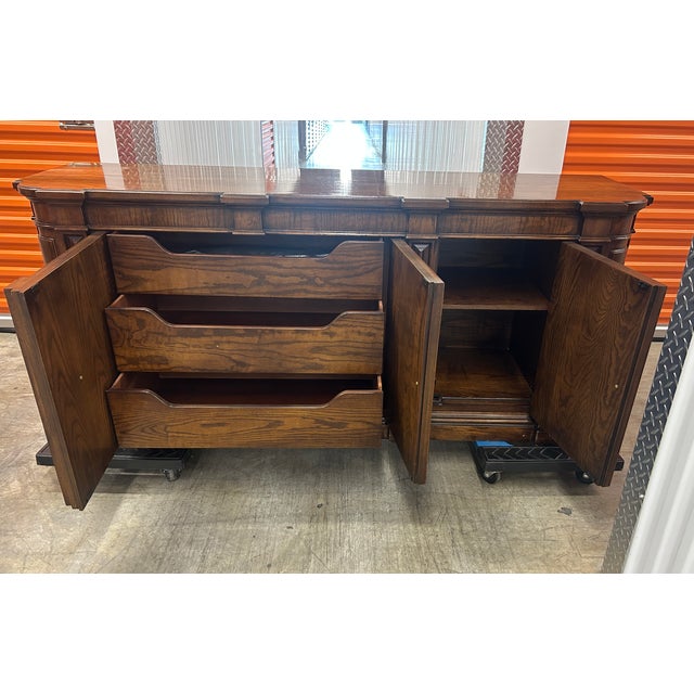 This is a vintage Henredon buffet crafted in rich walnut with a warm, medium-dark finish. The piece features elegant...
