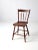 An antique Windsor-style accent chair featuring a decorative spindle back, a shaped wooden seat, and gracefully splayed...