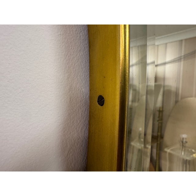 An Italian brass wall mirror, circa 1970s. The mirror is distinguished by its elongated, sculptural form with softly...