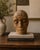 A striking contemporary studio ceramic head sculpture with a serene, introspective expression and richly textured earthen...