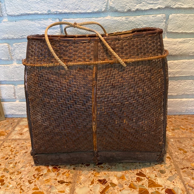 An antique early 20th century woven carrying grain basket from the Philippines with wooden base. Charming our eyes with...