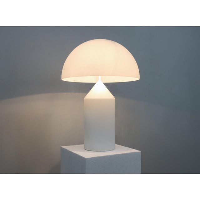 Refined elegance meets geometric perfection. This large atollo table lamp by oluce, crafted in the 1980s in white opaline...