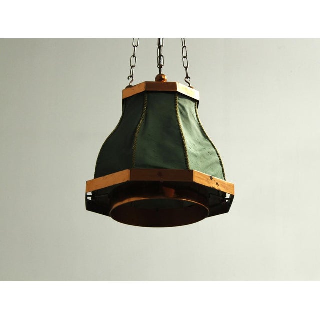 A copper pendant lamp with a fabric shade, suspended from four copper chains. The lamp is in its original condition with a...