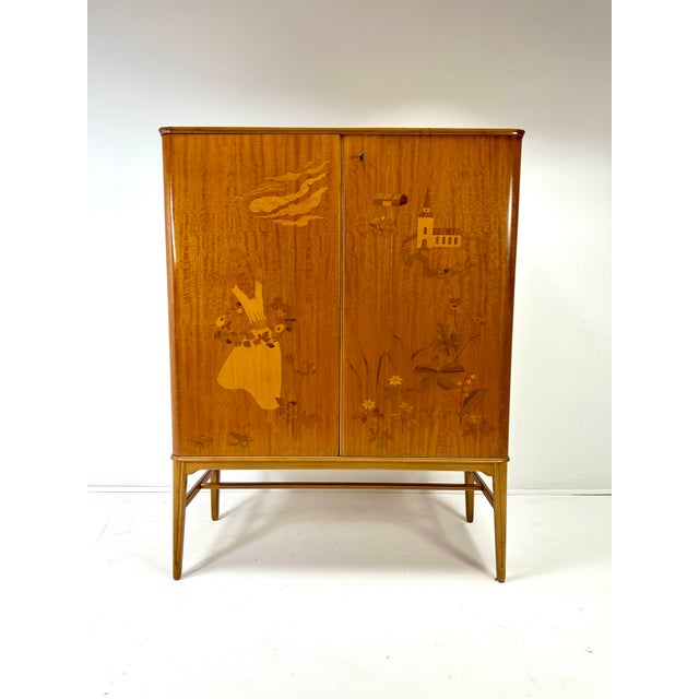 1940’s Swedish Cabinet designed by Erik Mattson. Beautiful intarsia woodworking creating a scene. Doors conceal interior...