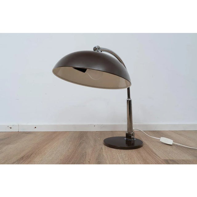 Model 144 desk lamp by H. Busquet for Hala Zeist. The light comes with a brown coated metal shade and base. The frame is...