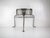A custom, handmade petite steel side table featuring an industrial silhouette with flared legs and a front skirt detailed...