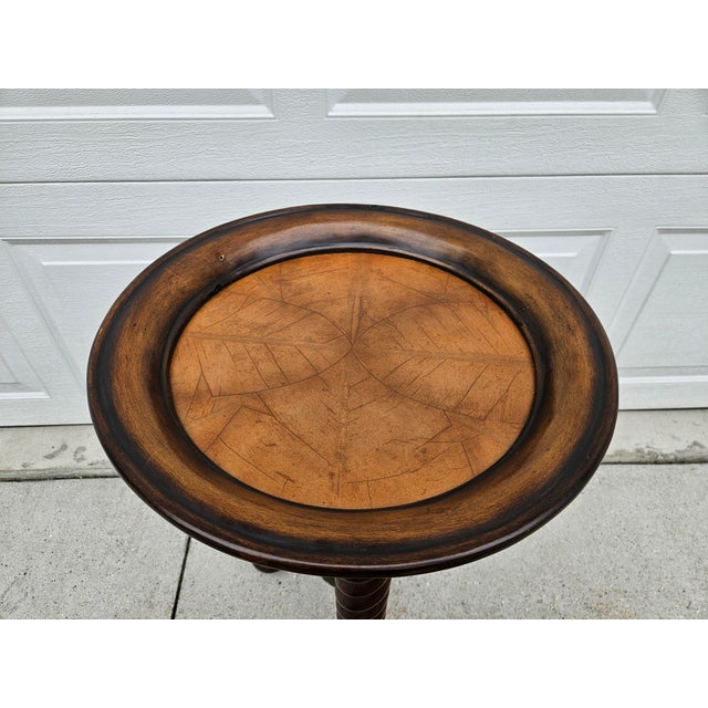 This beautiful round barley twist side table has a fixed tray top design with stylized palm leaves on the tabletop. The...