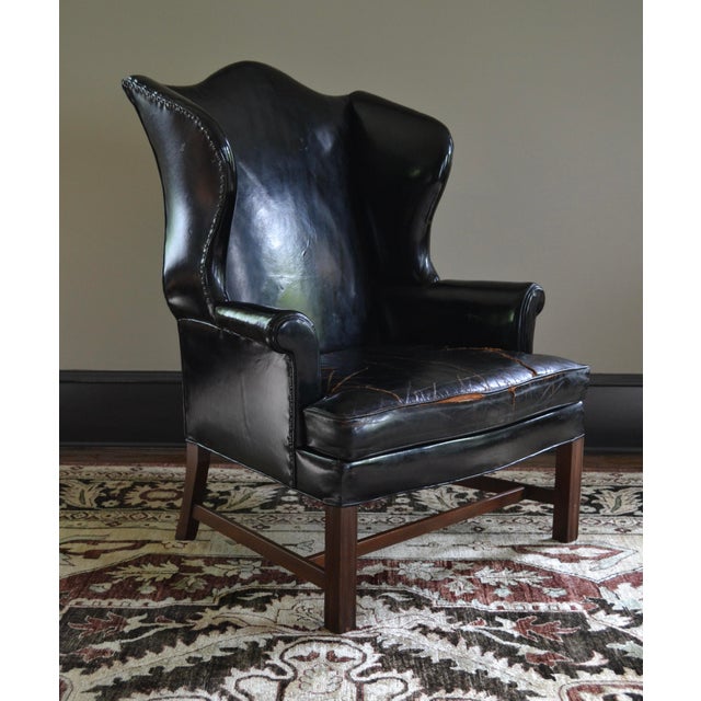 Great high quality early Kittinger Chippendale Style wing chair. Black leather with black nailheads. The design was a...