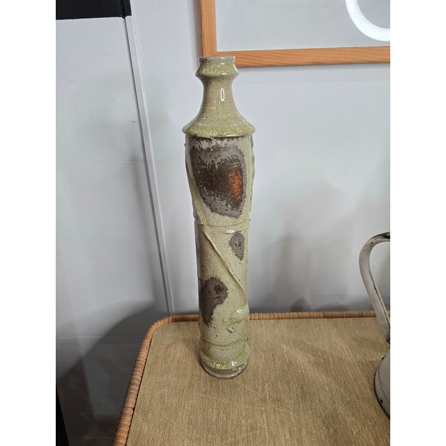 A slender vase in glazed stoneware, with a decidedly sculptural presence. Its highly graphic, vertical form evokes both a...