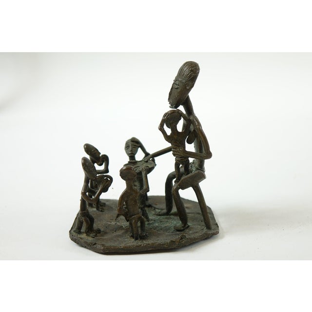 This antique African bronze sculpture depicts a family scene, with a larger father figure surrounded by children,...