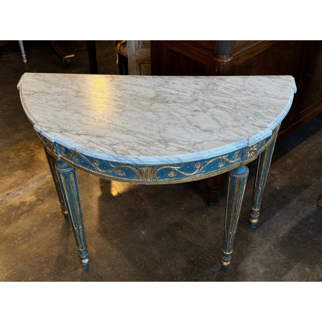 An 18th century Italian console with a shaped marble top set above a painted frieze decorated with gilt scrolling vines...