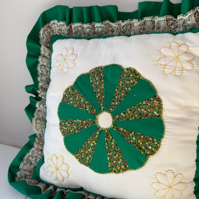 Vintage handmade quilt square ruffle pillow with stitched flowers and lace trim.