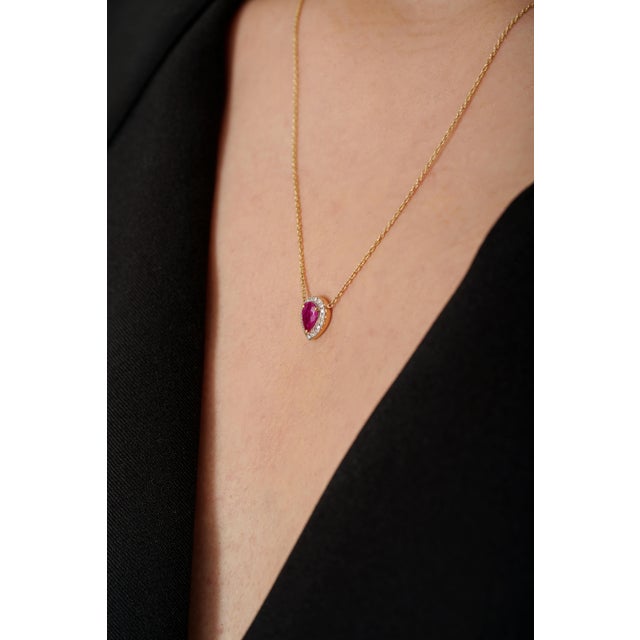 This elegant pendant necklace featuring a 0.39 carat pear-cut ruby set in 18K yellow gold. The ruby measuring...