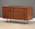 A mid century modern teak credenza with a swinging door, four drawers, and inset pulls designed by Arne Vodder for Sibast...