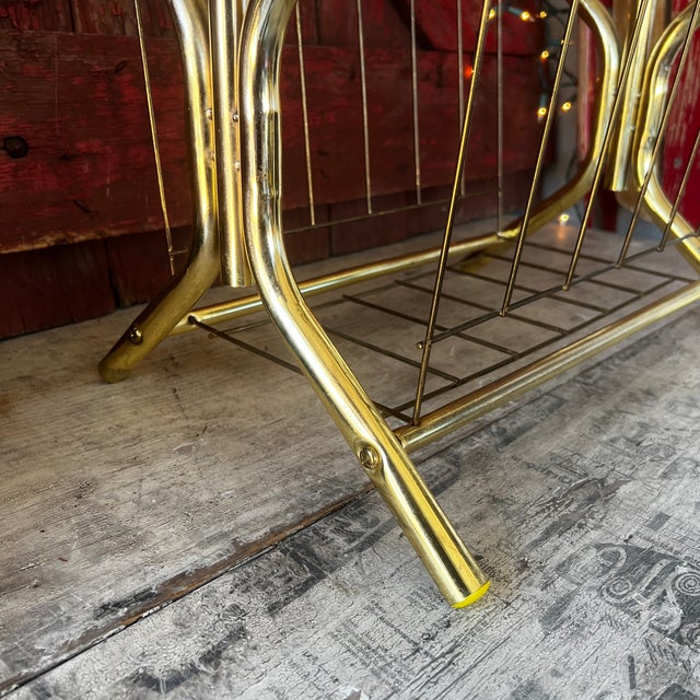 This vintage magazine rack combines form and function with its brass frame and tempered glass top. A timeless mid-century...