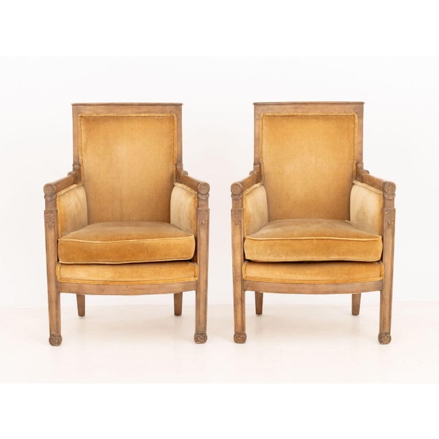 Pair of Restauration Style Fruitwood Bergeres, with golden velvet upholstery and carved rosette motif. 36.25" H x 25" W x...