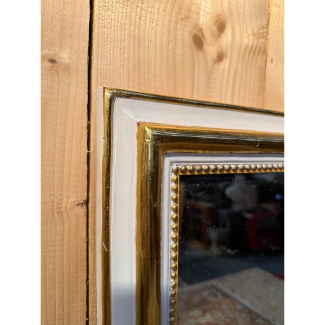 A louis xvi style rectangular vertical mirror with a white lacquered and gilded wooden frame. the frame consists of an...