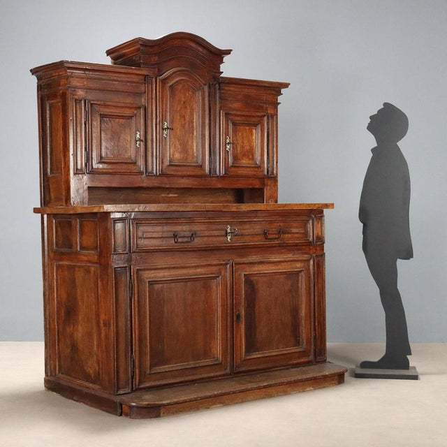 Baroque double-body walnut sideboard. The three-door cabinet features a taller central door with a curved moulding, a...