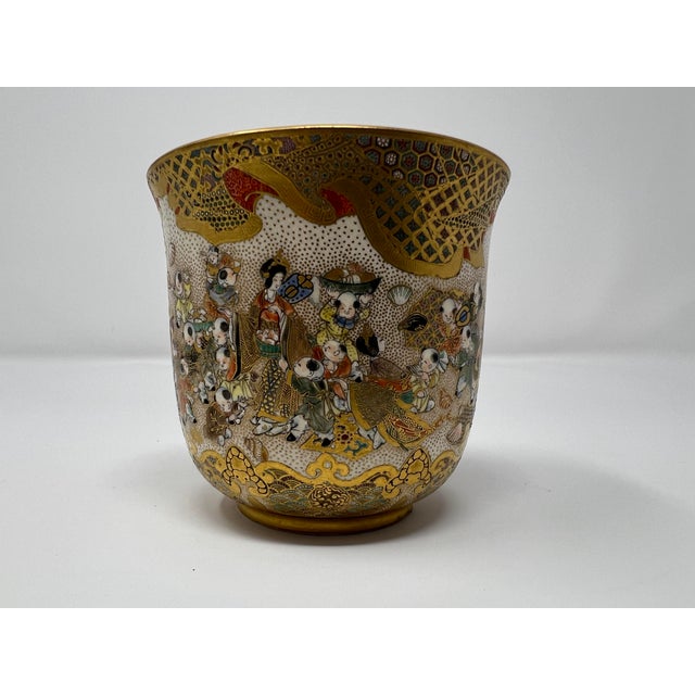 An intricately hand-painted Japanese Satsuma pottery vessel featuring lively karako children and a court scene, richly...