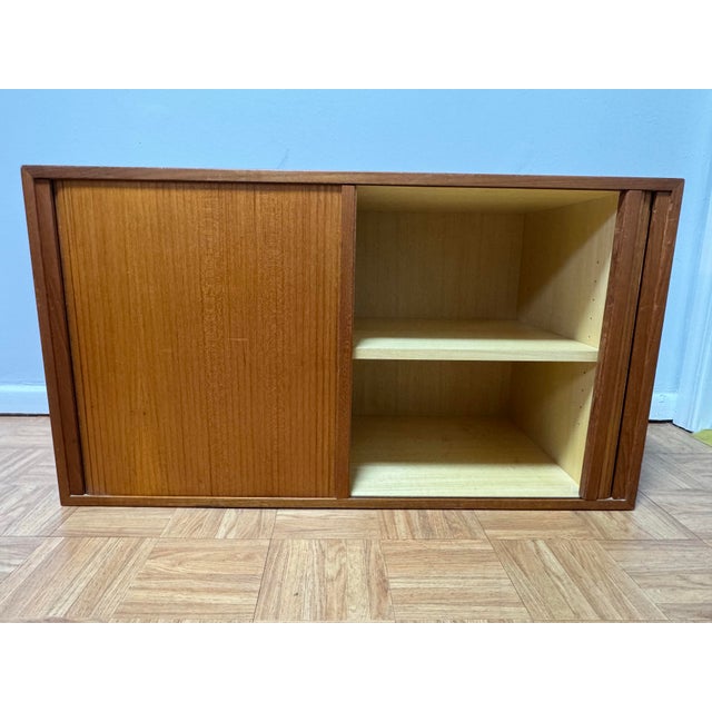 A refined Danish modern teak cabinet produced by HG Furniture and crafted in Denmark during the late 1950s–1960s. This...