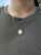 A luminous 6.36 carat Ethiopian opal takes center stage in this captivating pendant, cradled in a halo of natural, earth-...