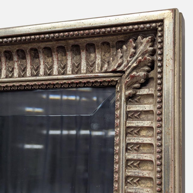 Carved mirror with corner leaves and beading along the perimeter. Original Price: $2500. Dimensions (in): 33W x 2D x 72H.