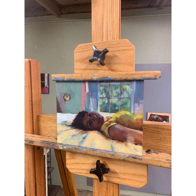 This oil on panel artwork captures a serene moment of intimacy, featuring a figure reclining in a softly lit interior. The...