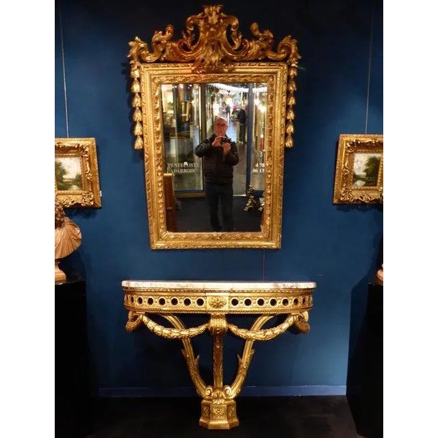 Very beautiful gilded wood set including a half moon console and a mirror. The shell of the mirror is very in relief. This...