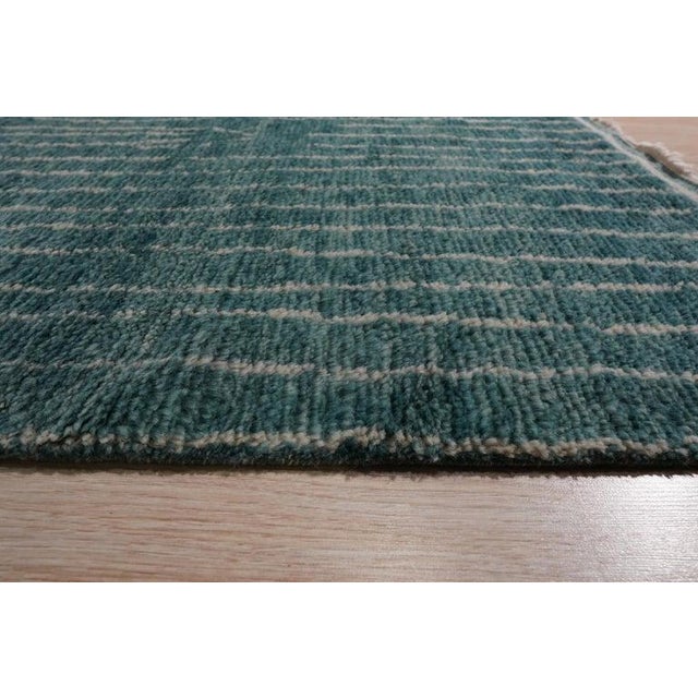 This green wool rug features a hand knotted pile construction that reflects the texture of traditional Berber carpet...