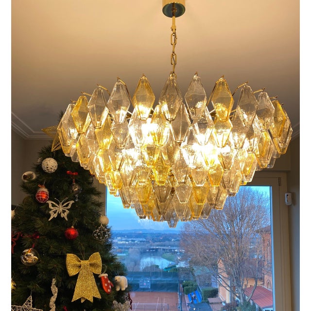 This chandelier consists dozens of hand blown gray , amber and clear "Poliedri" made of Murano glass with a brass frame....