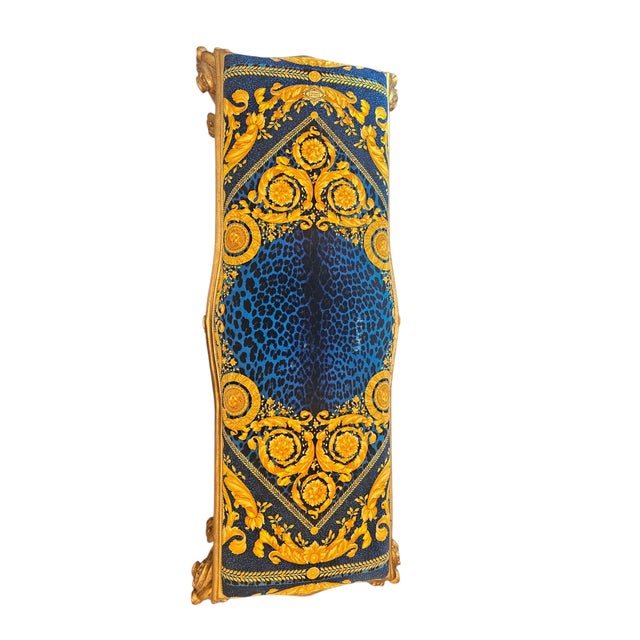 The bench is in Baroque style with giltwood carved wood featuring striking blue and gold patterned upholstery with animal-...