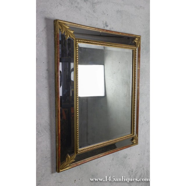 An elegant French carved giltwood mirror dating to the late 19th century, featuring a beautifully detailed giltwood frame...