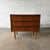 A Danish teak three-drawer chest from the 1960s with slim integrated pulls, tapered legs, and a compact raised case. The...
